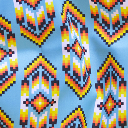 A repeated Native American bead-inspired design with a white, orange, yellow and black geometric bead design on a light blue background