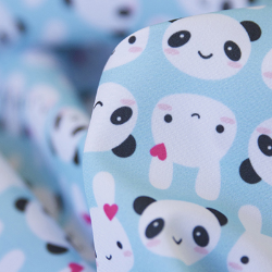 Small rows of black-and-white pandas with pink cheeks and white bunnies with a heart hairpin and pink cheeks repeat on a light blue background. 