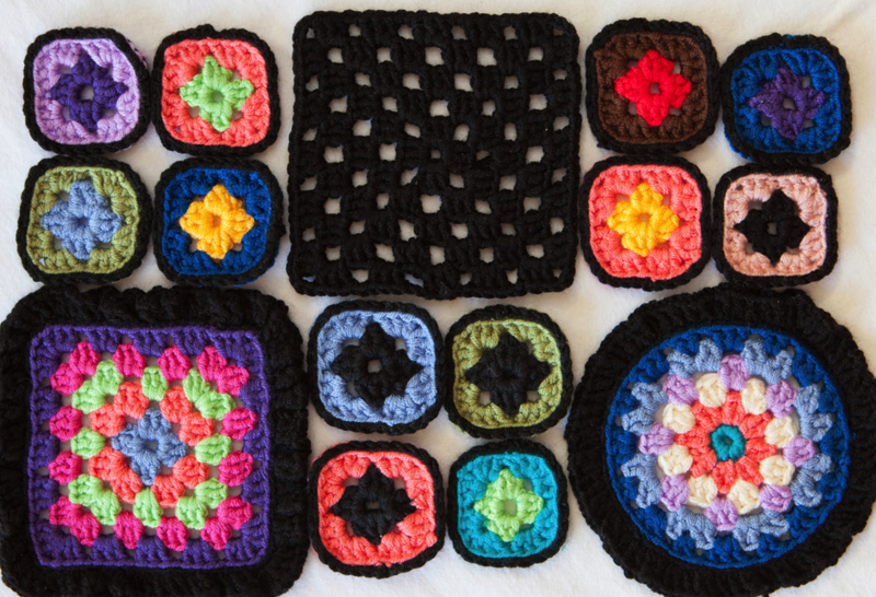 Granny squares of varying sizes are laid out on a white surface. 