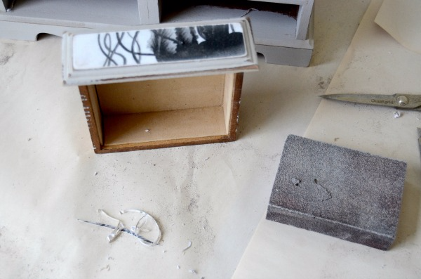 A small drawer with black-and-white jellyfish wallpaper on the front sits next to a sanding block. 