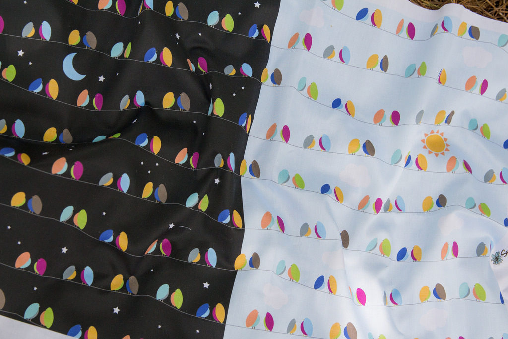 printed fabric, half black, half white, with modern colorful bird shapes sitting on lines