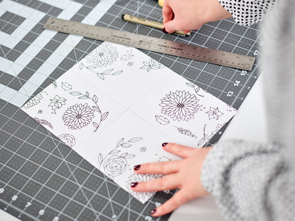 Drawings of flowers on a piece of paper, being measured with a cutting mat and ruler