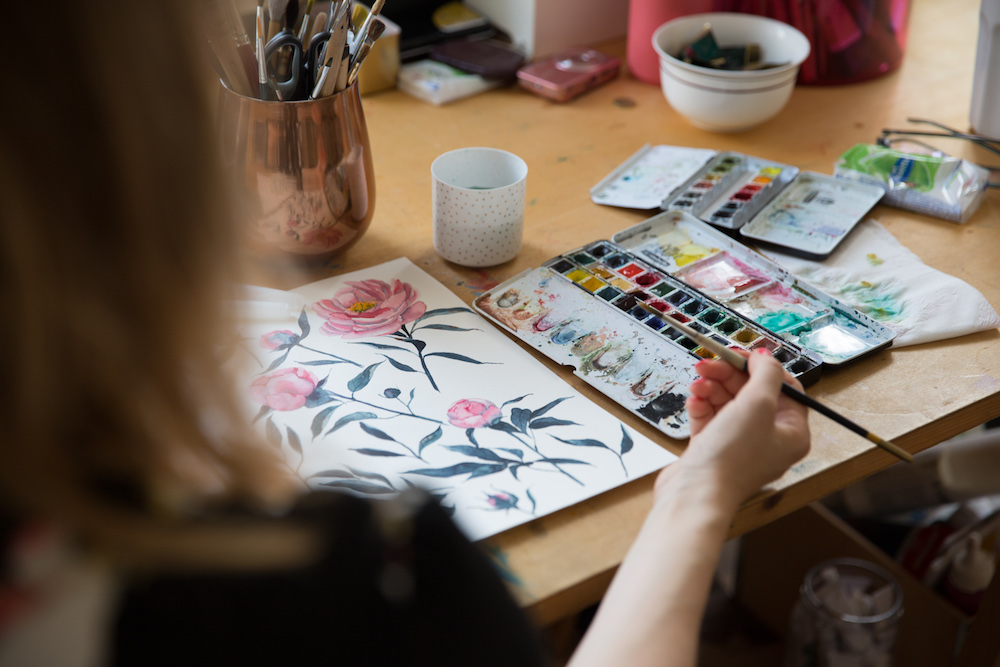 Artist paints flowers with watercolor paints