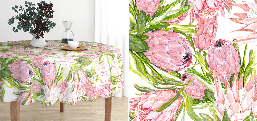 Two images of Michelle Aitchison's "Prettiest Proteas" design. On the left is the design as used on a tablecloth. The table has a green floral arrangement in a white vase on it, along with a glass coffee pot and a white coffee cup on a wooden tray. The table's wooden legs are visible underneath the edges of the tablecloth. On the right is a closeup on of the print, bright pink proteas fill the image with bright green leaves around them. 