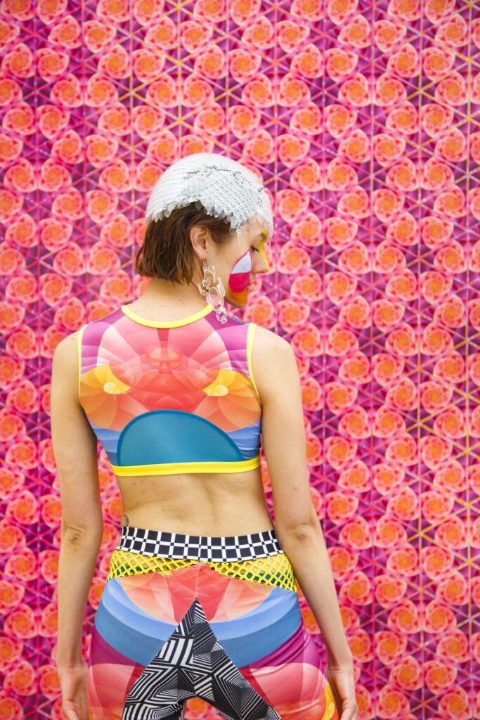 Colorful outfit worn by a model with face paint in front of bright pink geometric wallpaper | Spoonflower Blog 