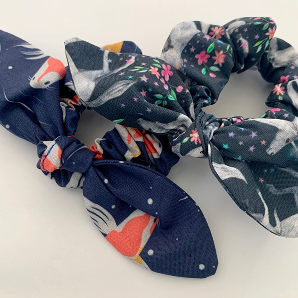A blue headband with Koi fish is between a white surface and another blue headband with unicorns.