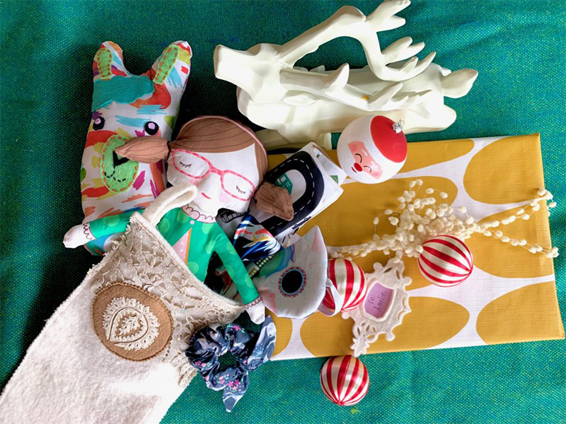 A doll, bowtie, and fabric llama hanging out of a stocking are surrounded by a green background.