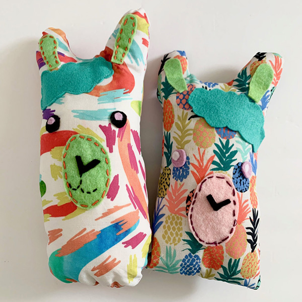 Two llamas in two multicolor designs are on a white background.