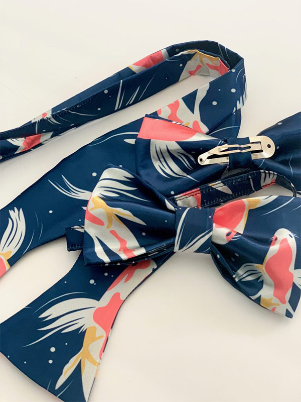 A blue bowtie with Koi fish on a white surface.
