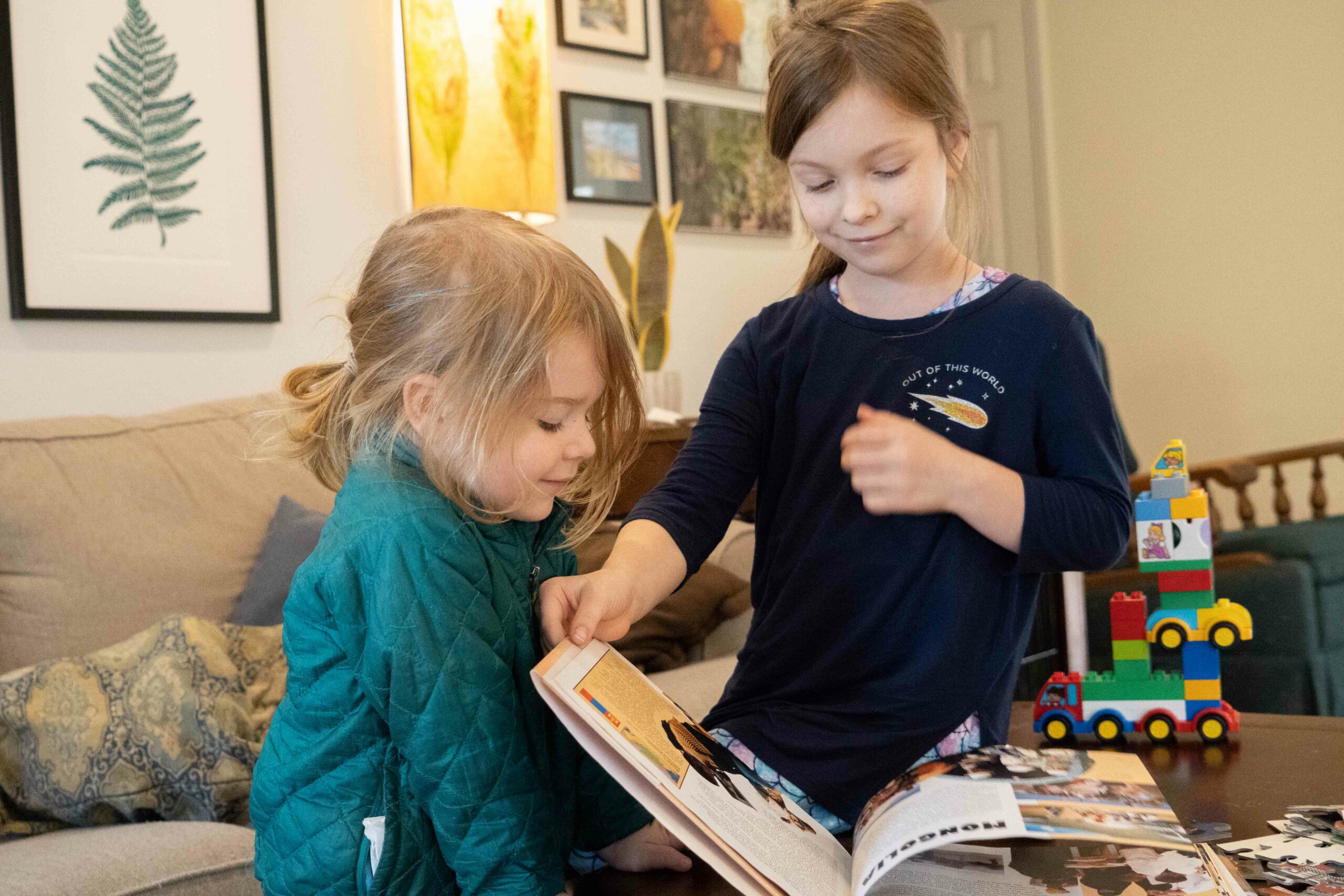 Katie's children flip through a book near some of their toys