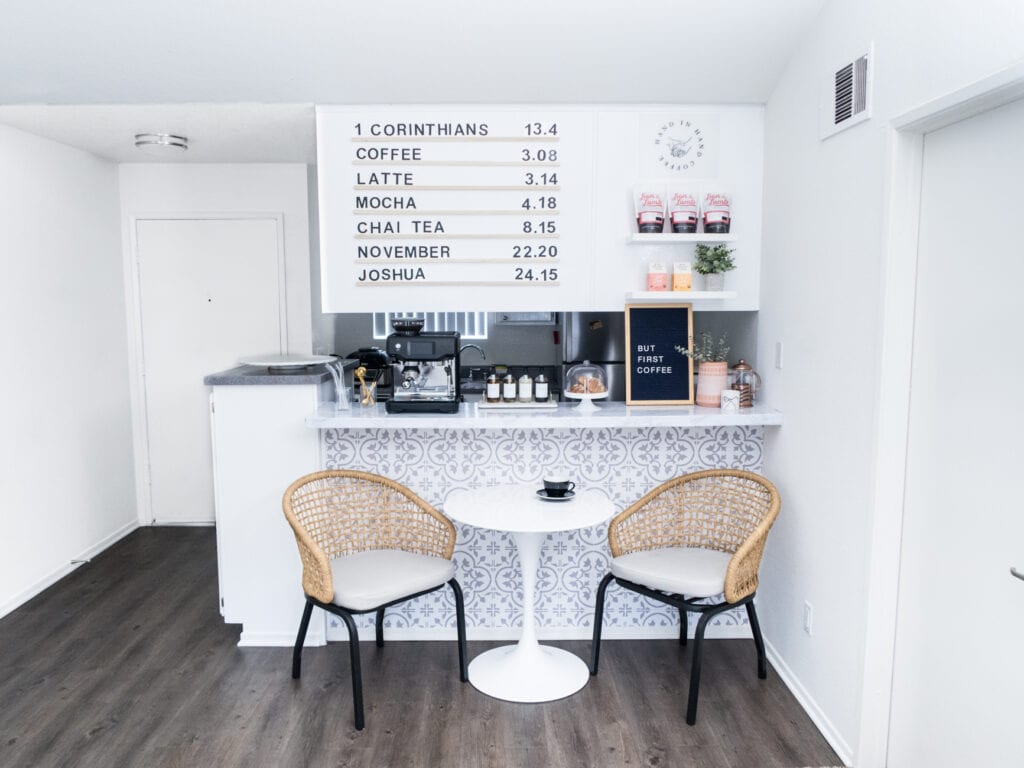A cafe has been recreated in a kitchen with a menu board, grey and white wallpaper and a table with two chairs