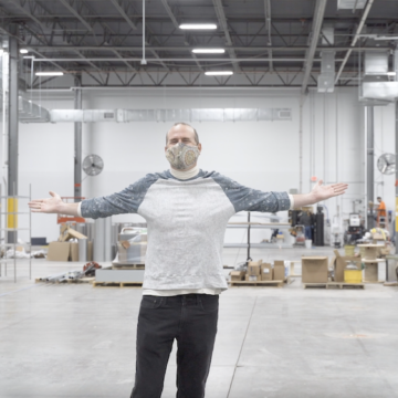 Gart stands in a large factory space with his arms outstretched