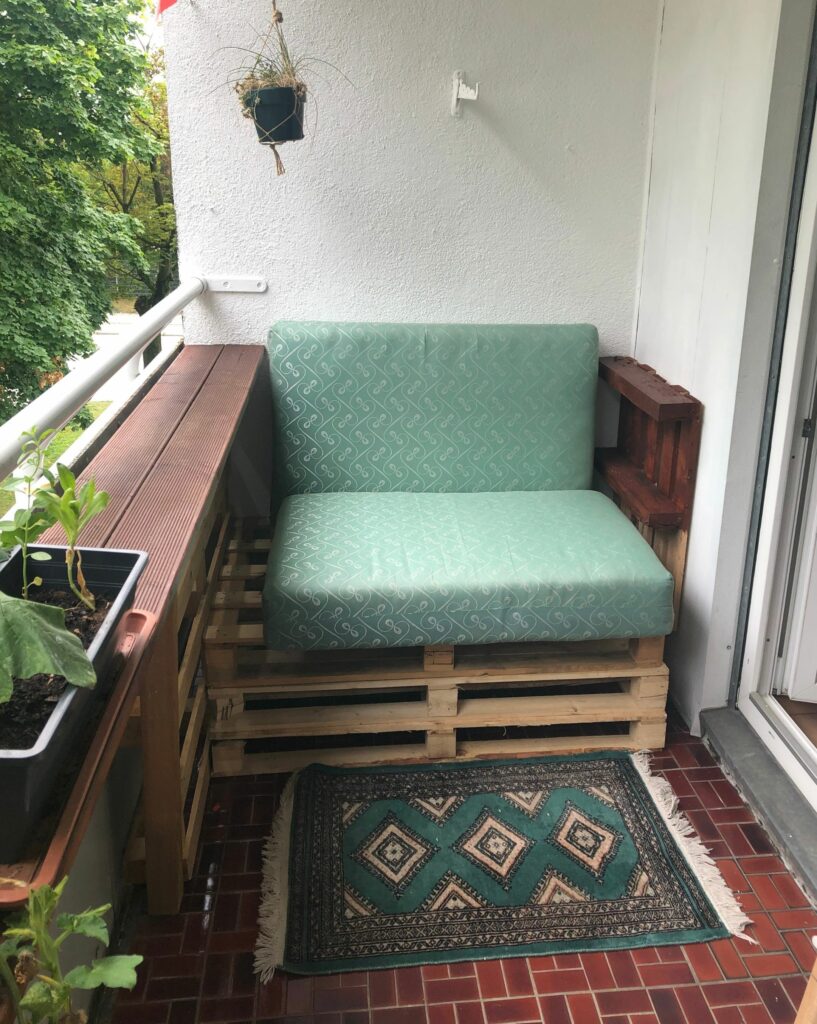 Before balcony transformation, green outdoor couch with green rug