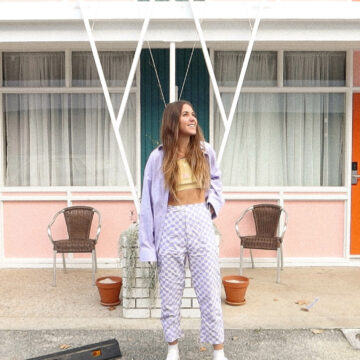 Maddy wears purple and white checkered pants in front of a retro building
