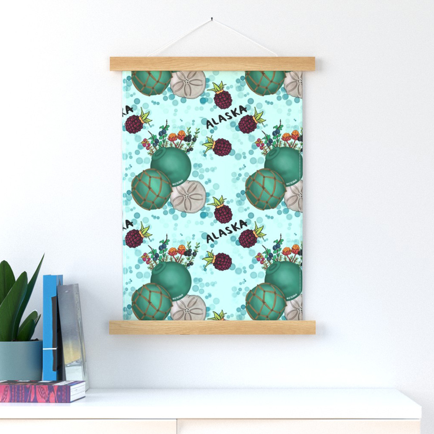 Malorie’s Alaska Treasures design is shown on a Spoonflower wall hanging. This teal and mint colored design features glass balls, sand dollars, mossberries and salmonberries from her native Alaskan environment.
