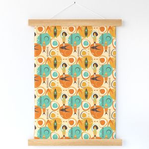 A wallhanging hanging against a white wall features dark orange and light orange rocketships pointing upward into space. Geometric shapes, including large dark orange and turquoise circles float on top of a cream background. Strips of wood are at the top and bottom of the wallhanging, ensuring it holds taut and in place.