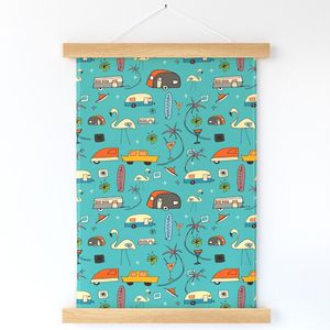 A fabric wallhanging hanging against a white wall features vintage camper vans, flamingo yard ornaments, palm trees, martini glasses, cars towing campers and small orange spaceships appear on a turquoise background. Strips of wood are at the top and bottom of the wallhanging, ensuring it holds taut and in place