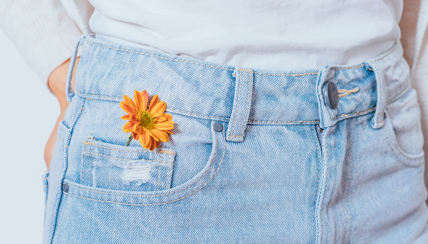 A yellow flower tucked into a jean's pocket