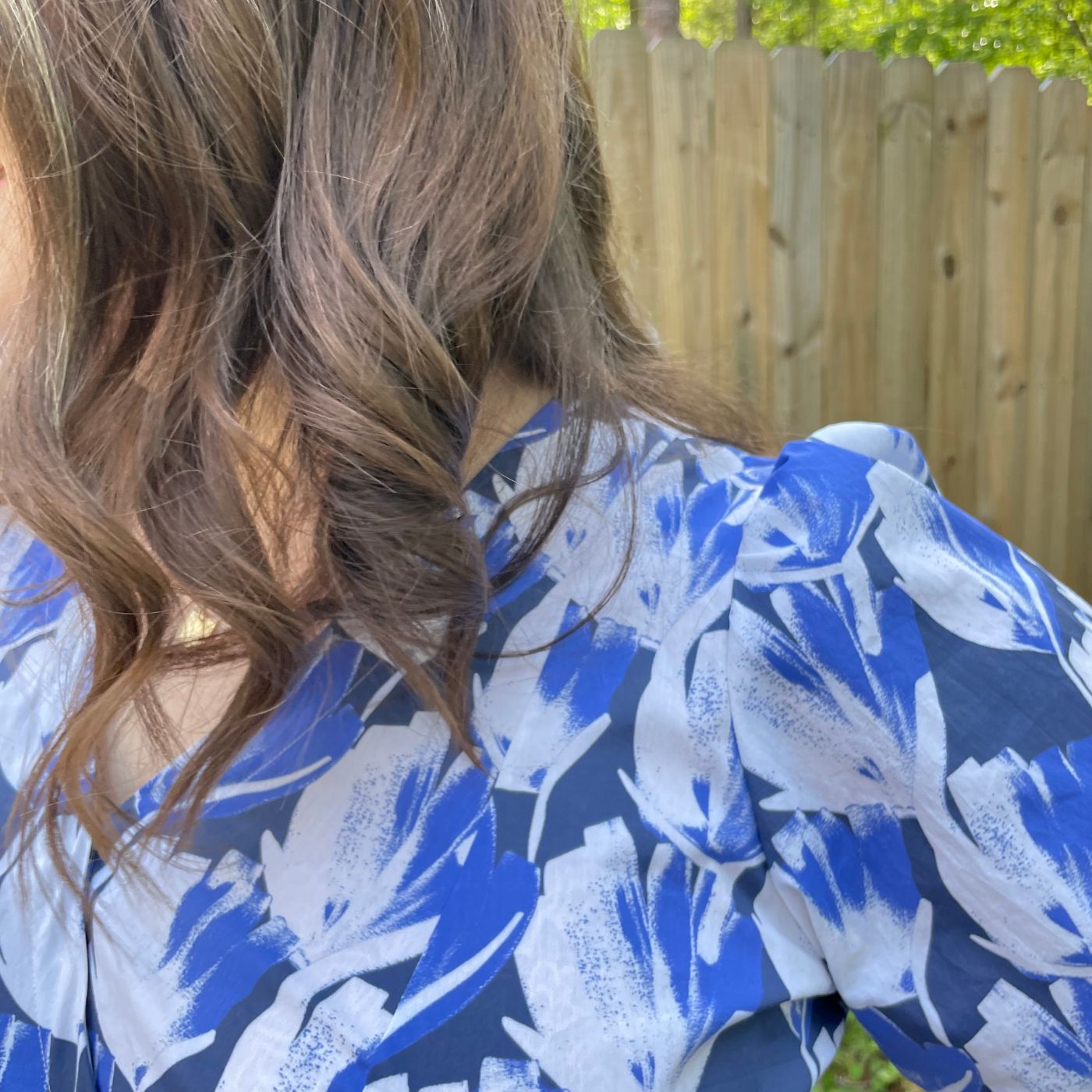 A close up of MaryAshlyn’s dress at the shoulder. The dress has repeating white and blue flowers on a navy background.