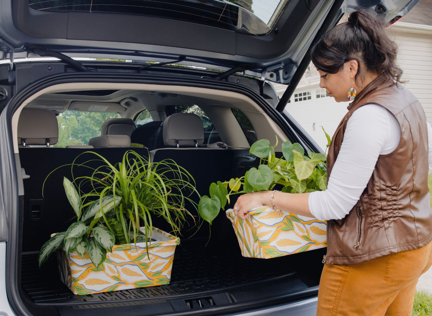 Stephanie placing two plants into the back of an SUV car.