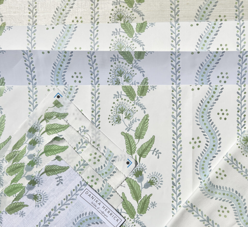 Several different swatches of fabric and wallpaper laid closely together and comprised of narrow vertical columns of light blue leaves and green dots with alternating columns with vines featuring green leaves and light blue flowers