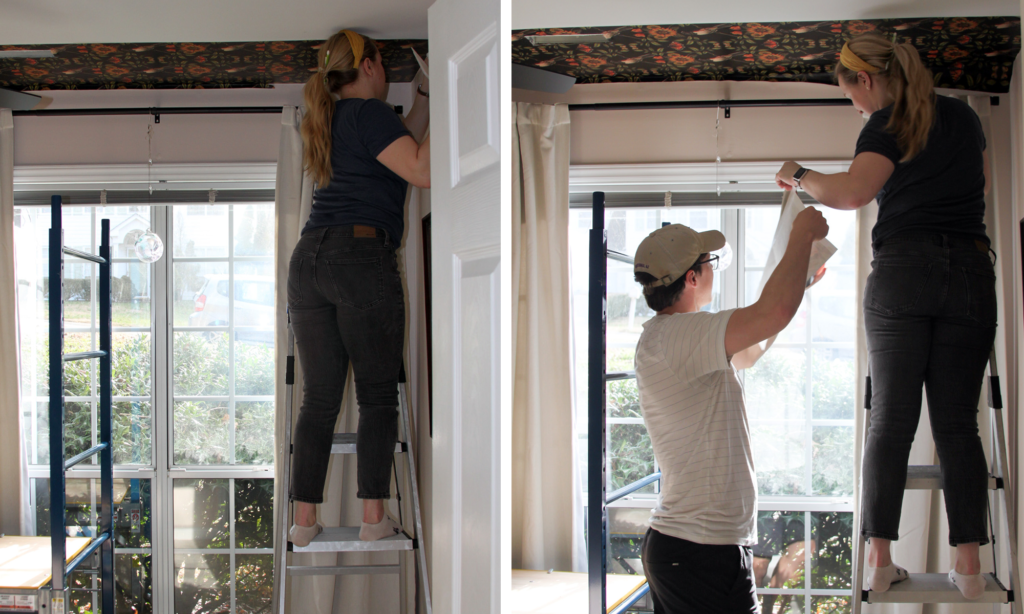 a white man and blonde woman stand in front of a window installing ceiling wallpaper. 