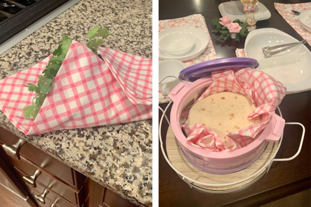Two images have been placed side by side. On the left, fresh cilantro is wrapped in a pink-and-white gingham tea towel sitting on a stone gray, black and white countertop. On the right, flatbread has been placed in a warmer with a pink-and-white gingham tea towel wrapped around them. Cherry blossom dinner napkins are used as placemats at two settings at a wooden table. White ceramic cups, plates and bowls are at each table setting. A white ceramic serving platter in the center of the table next to a small angel figurine and two small rose figurines. The serving platter also as a cherry blossom dinner napkin folded underneath it.
