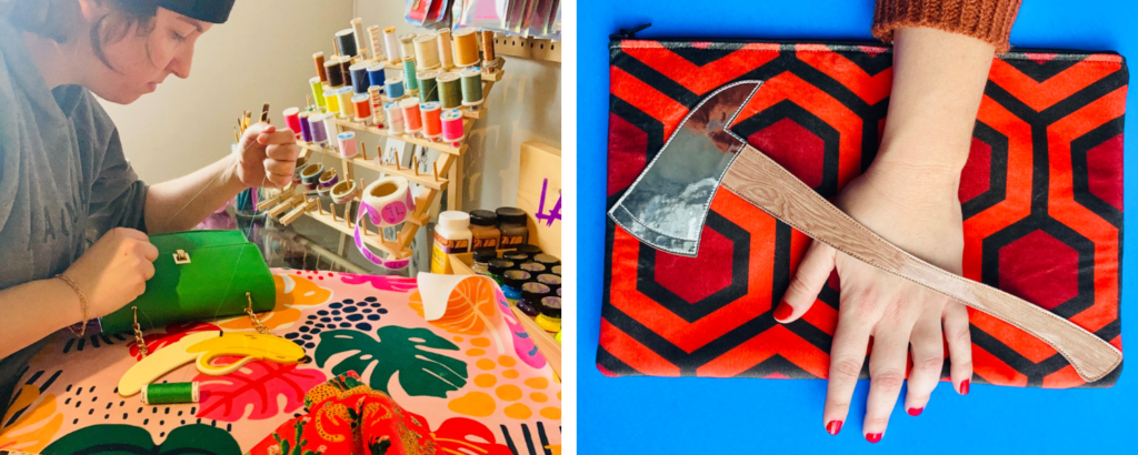 Two images have been placed into one rectangular image. On the left, Katelin sews a green purse in her workshop near colorful tiered spools of thread. Pink floral fabric is to Katelin’s left and red fabric with lions and cacti is closest to the camera. On the right, a hand grips a red, dark red and black geometric rectangular clutch with a faux leather axe placed as a handle running diagonally across the wide front side of the clutch. Behind the purse is a bright blue background.