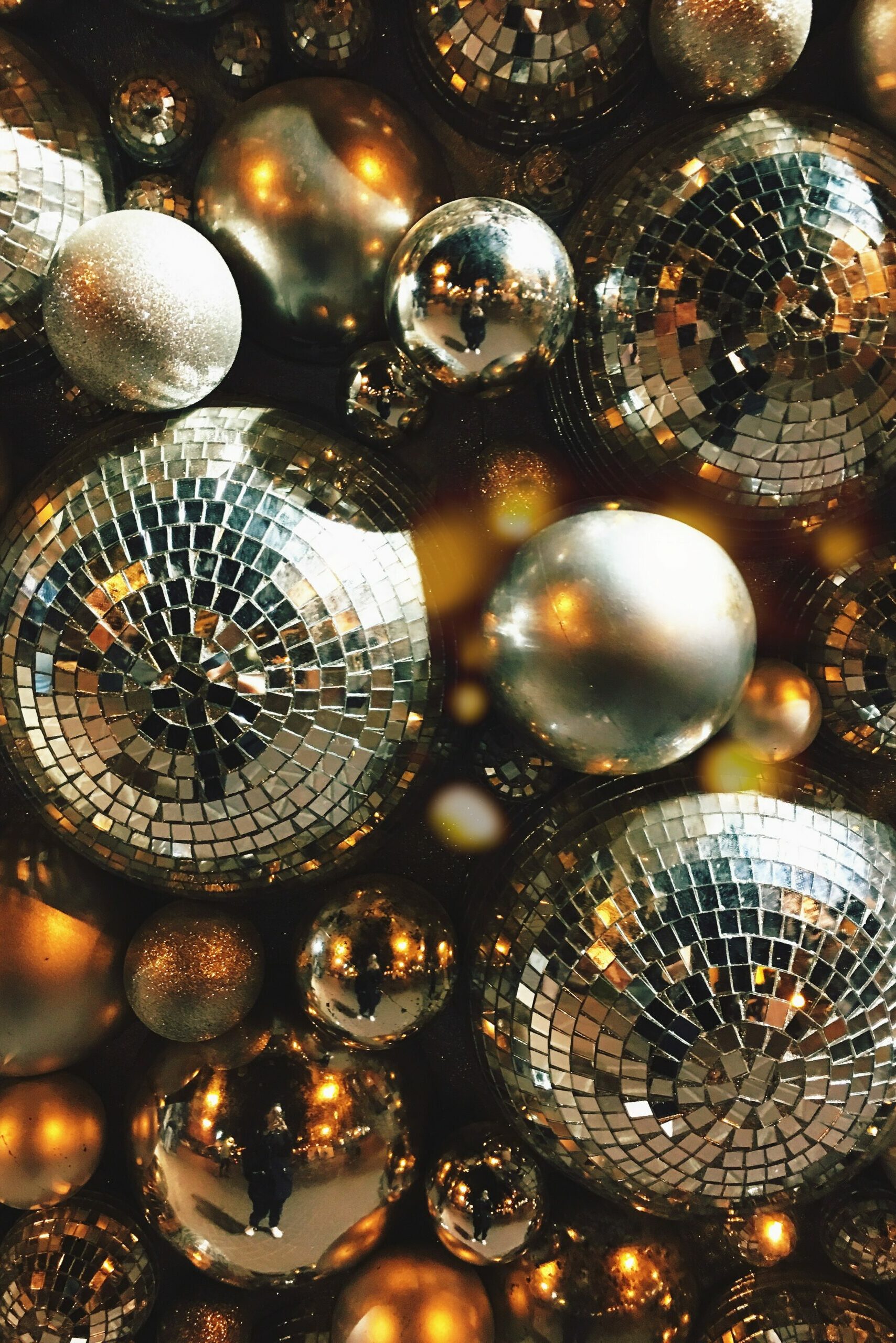 Disco balls of varying sizes have been hung together and are viewed from below.
