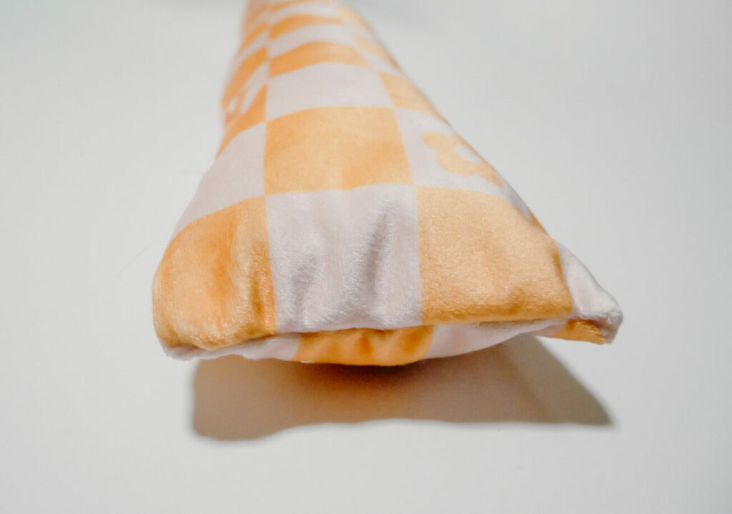 close up of white and orange checkered cushion end stitched closed.
