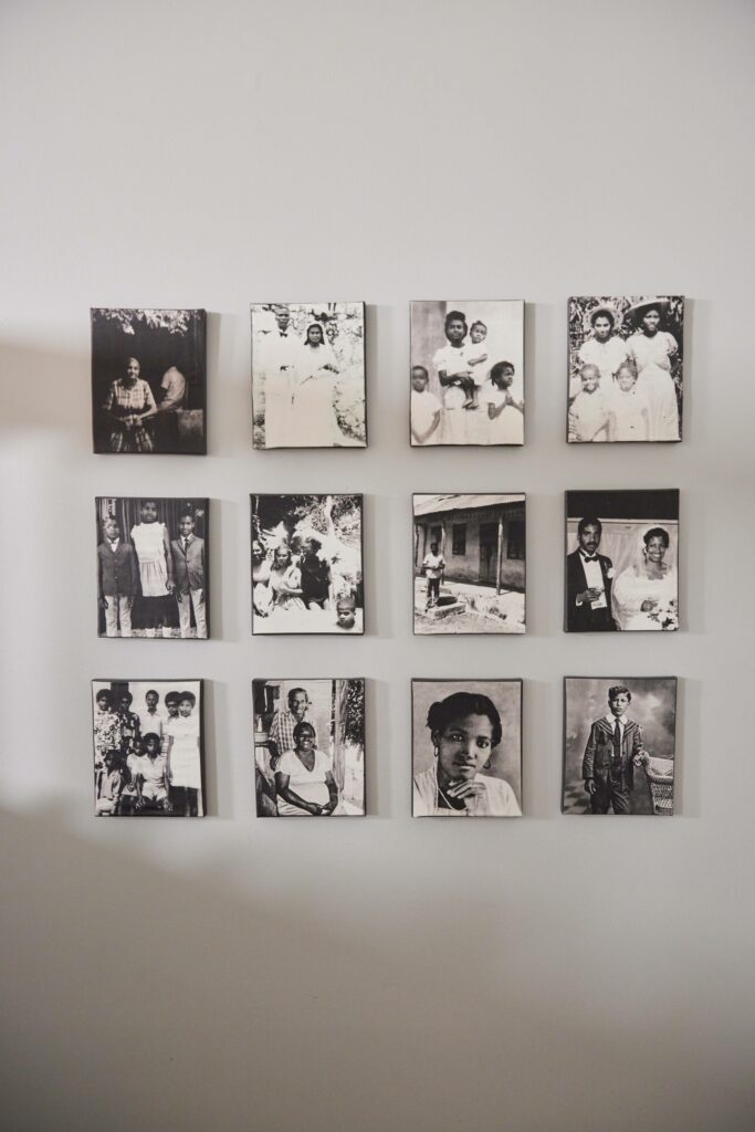 Twelve antique family photos are on twelve square canvases in front of a light grey wall.