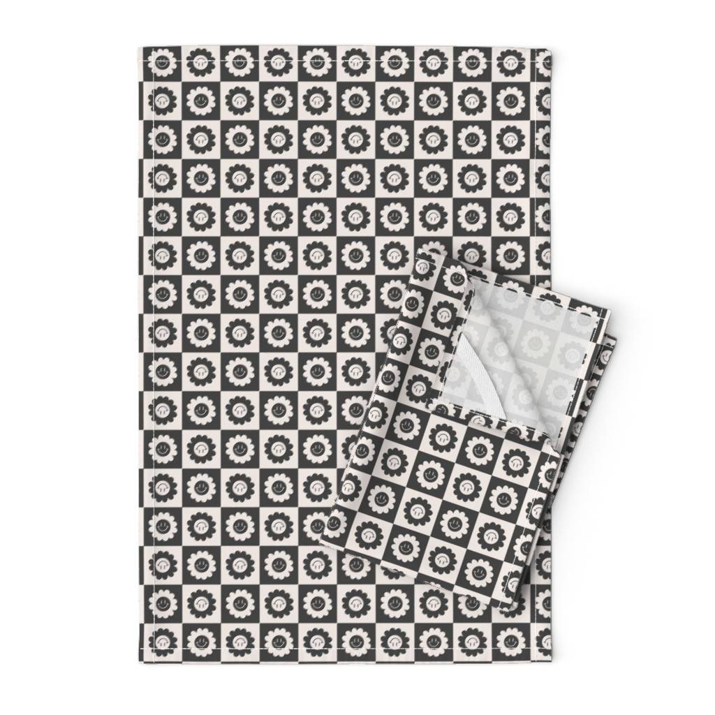 A black and white checkered towel with retro flower smiley faces in each box.