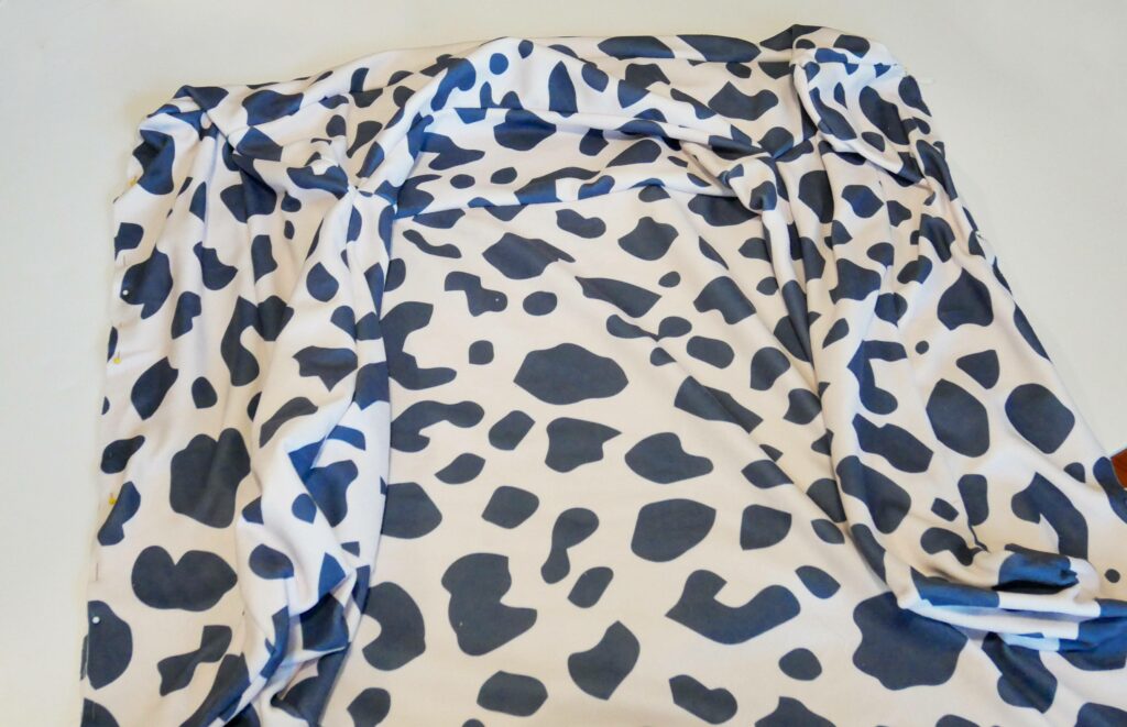 The bolsters are now sewn to the base of the dog bed. The fabric is white with black cow-print shapes.