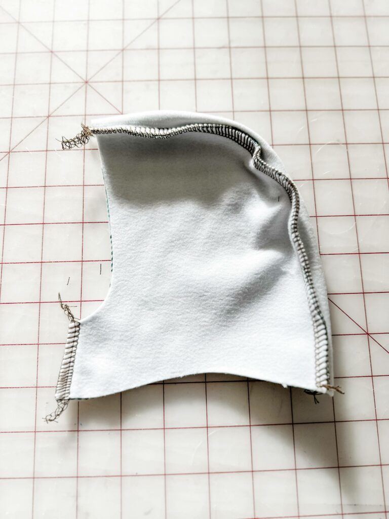 One of the hoodie’s side pieces is shown design side down and sewn to the curve of the center piece. The edges where the sewing clips were are now sewn together.