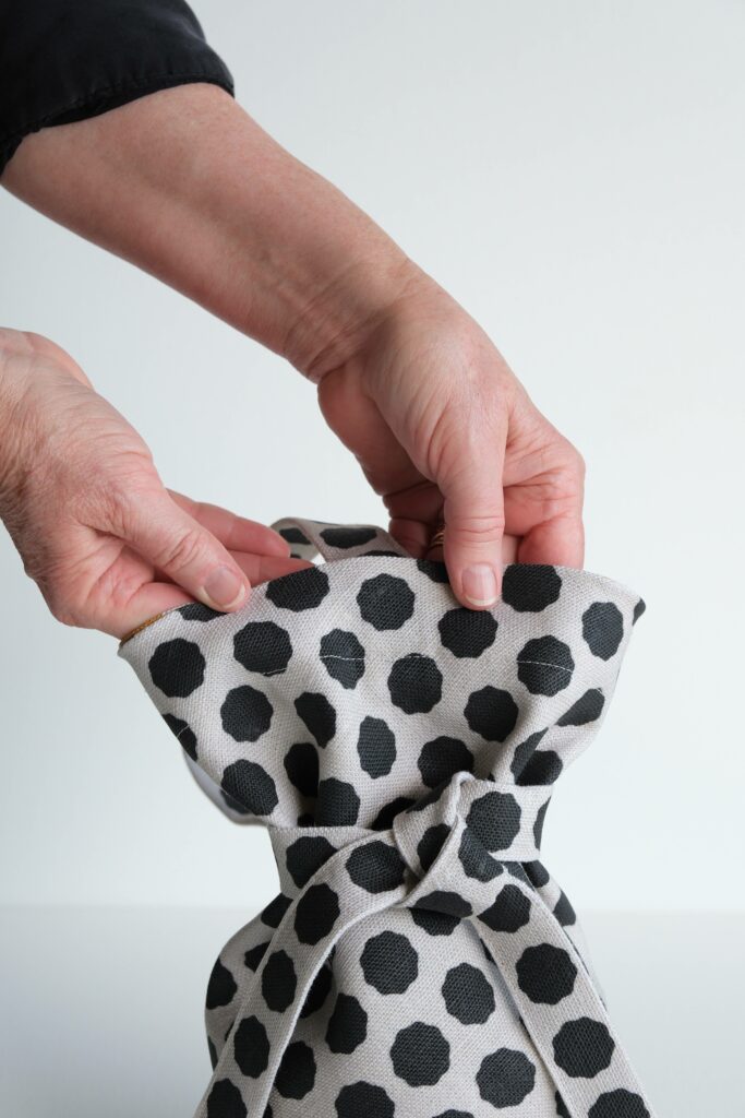 A closer look at how in the finished bag, there is a line of top stitching near the top edge of the bag. The bag’s fabric is white with black dots.