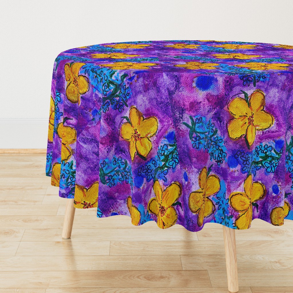 A round tablecloth with large yellow flowers and small forget me nots repeating on a bright purple background covers a table with light wooden legs.