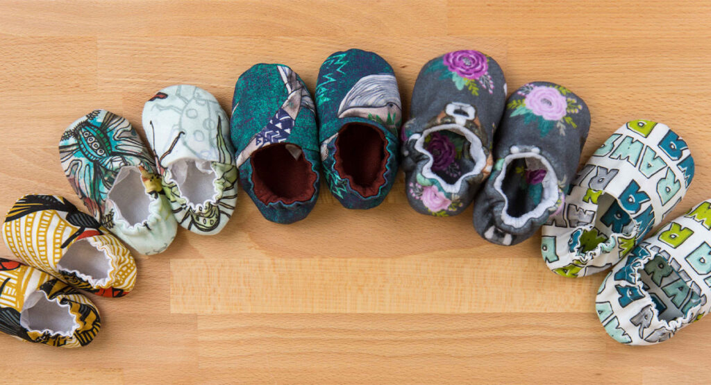 Bbay shoes in different designs lay across a wooden table in a semicircle.