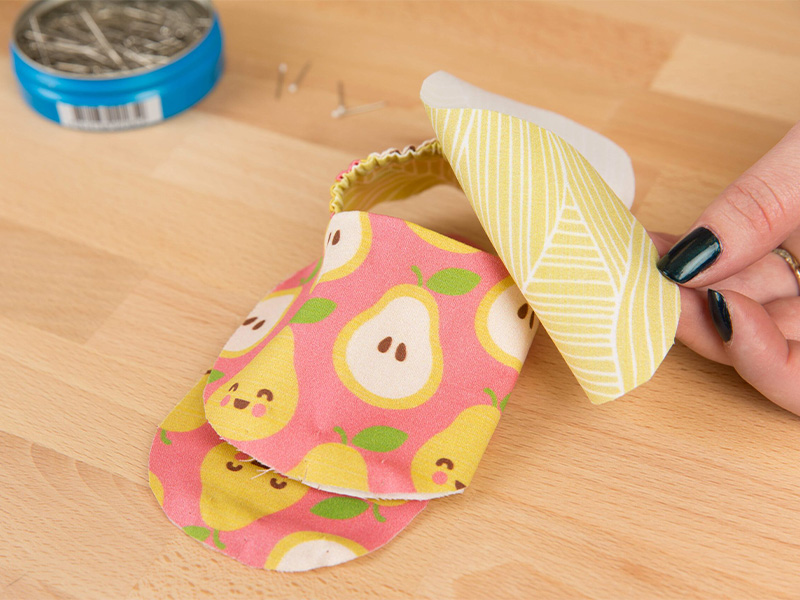 Fabric pieces for the bottom of the shoe are between the finished heel and toe pieces of the baby shoe.