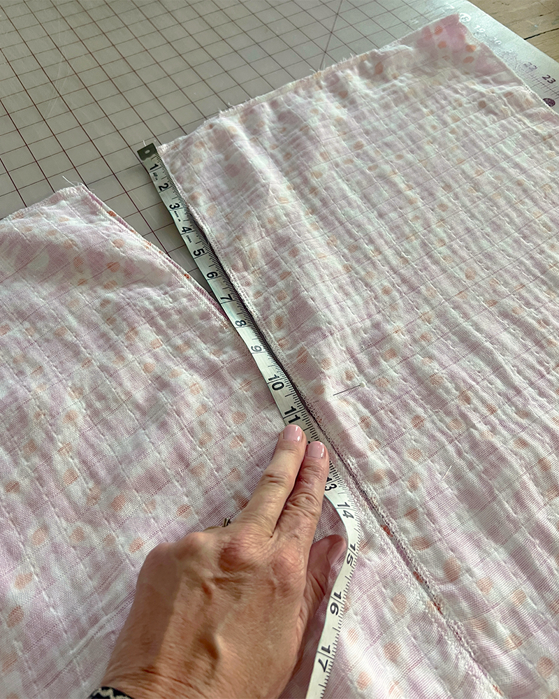 Measuring the back seam of the V neck with a white measuring tape.